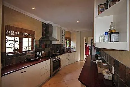 Long kitchen with light cabinets and a dark worktop