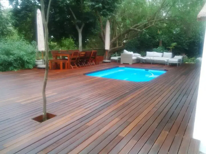 Outdoor timber decking around a blue swimming pool
