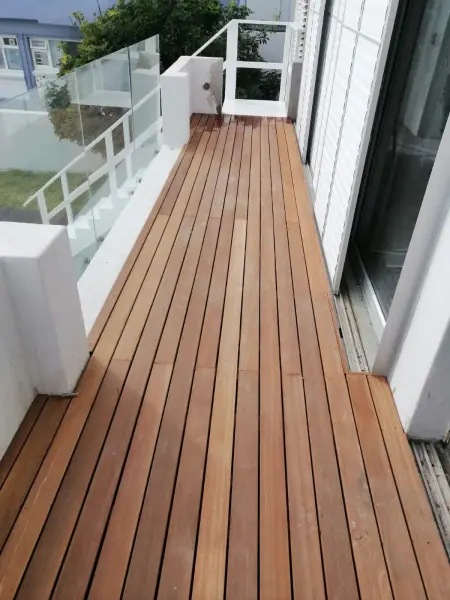 Timber walkway with a white balustrade beside a house