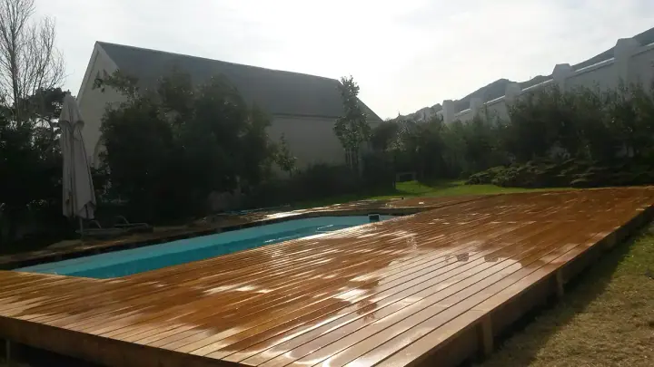 Wet timber deck boards beside a rectangular pool