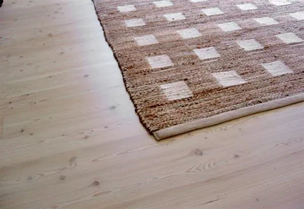 Close view of pale timber flooring beside a patterned rug