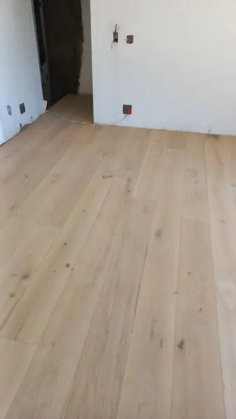 Light timber floorboards across a white room