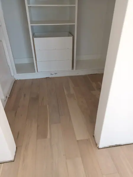 Timber flooring under a fitted white cupboard