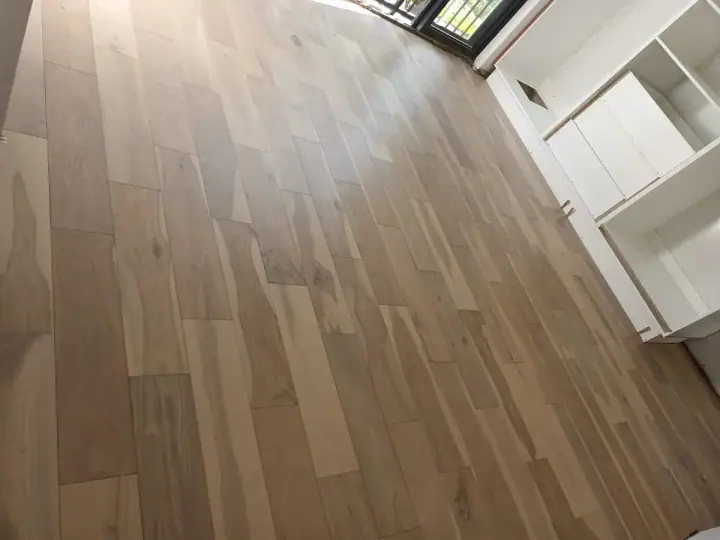 Light timber floorboards beside a white kitchen