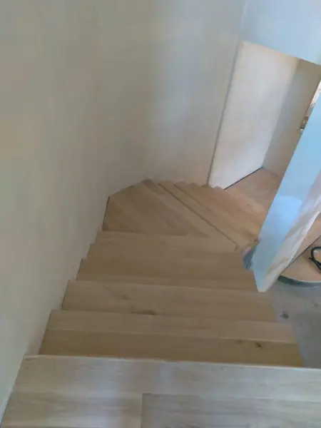Pale timber staircase descending around a turn