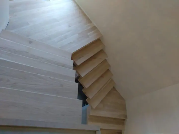 Timber staircase curving beside matching flooring