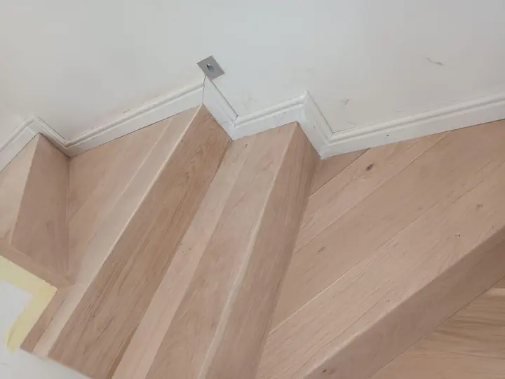 Turning timber staircase against a white wall