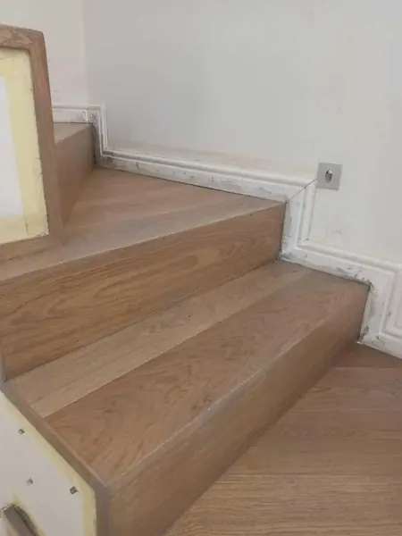 Close view of pale timber stairs and white skirting